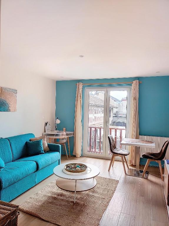 un salon avec un canapé bleu et une table dans l'établissement L'oasis d'Anatole, à Oyonnax