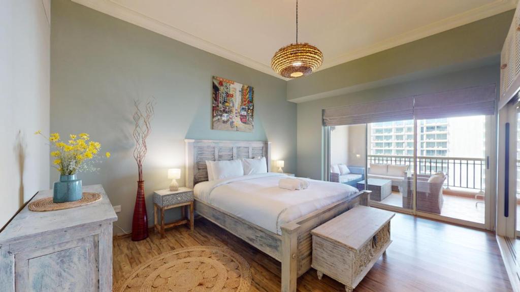 une chambre avec un grand lit et un balcon dans l'établissement Golden Mile 1 - Contemporary One Bedroom, à Dubaï