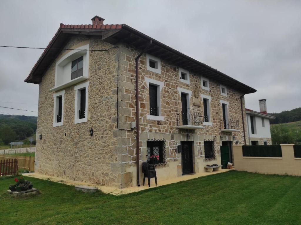 a large stone building with a grass yard at La casita de Mena in Hoz de Mena