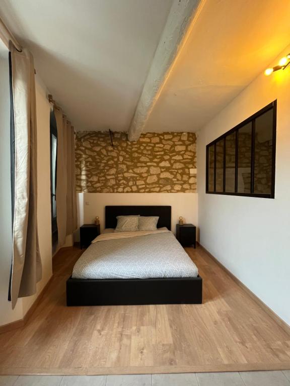 une chambre avec un lit et un mur de briques dans l'établissement Studio Carpentras, à Carpentras