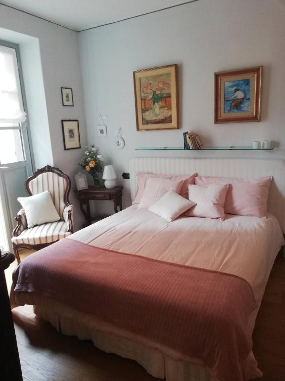 Un dormitorio con una cama grande con almohadas rosas. en A room in the &#39;borgo&#39;, en Dogliani
