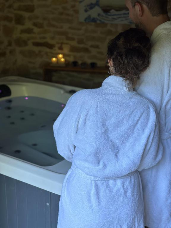 un homme et une femme debout devant une baignoire dans l'établissement Sous la glycine, à Sarrazac
