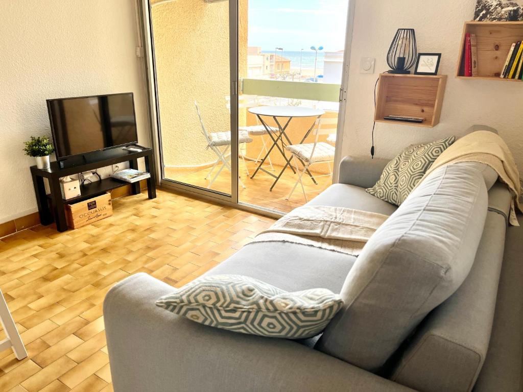 un salon avec un canapé et une télévision dans l'établissement Le Mailheul - Tout compris - vue mer - 160 m de la plage, à Narbonne-Plage