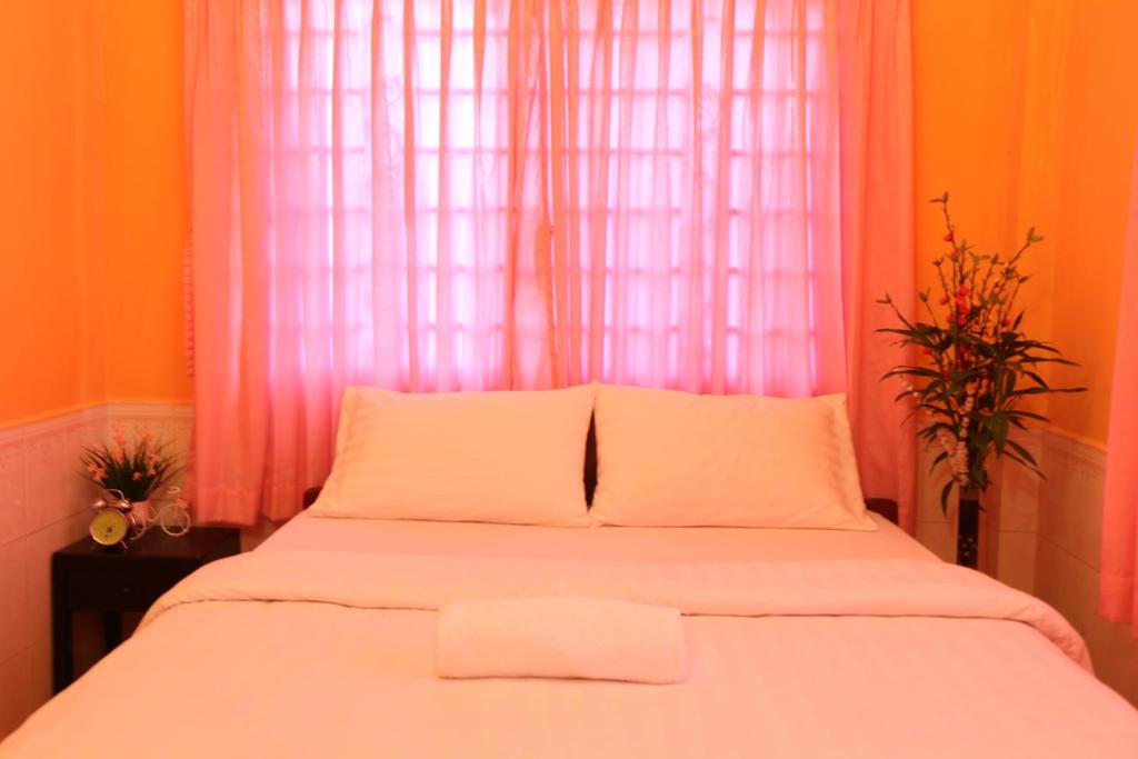 um quarto com uma cama branca e uma cortina rosa em Eco-Home Siem Reap Homestay em Siem Reap