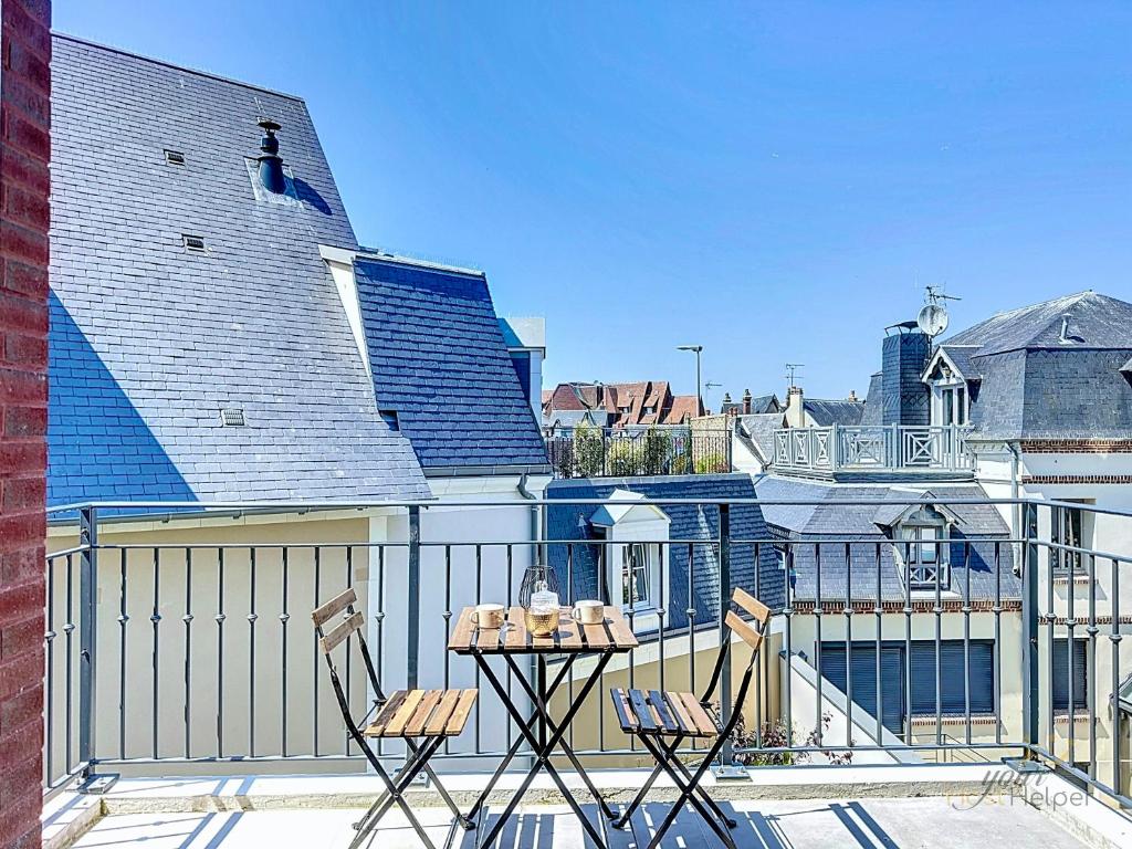 un patio avec deux chaises et une table sur un balcon dans l'établissement Opale YourHostHelper, à Deauville