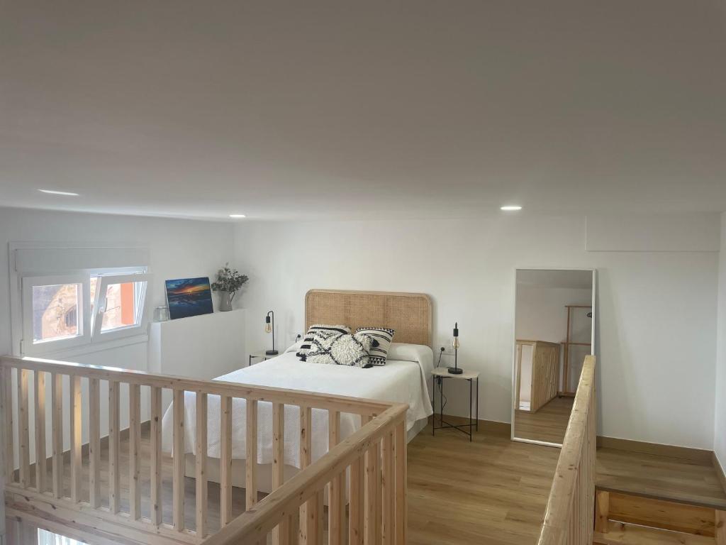 a white bedroom with a bed and a staircase at Apartamento de la Luz in Tarifa