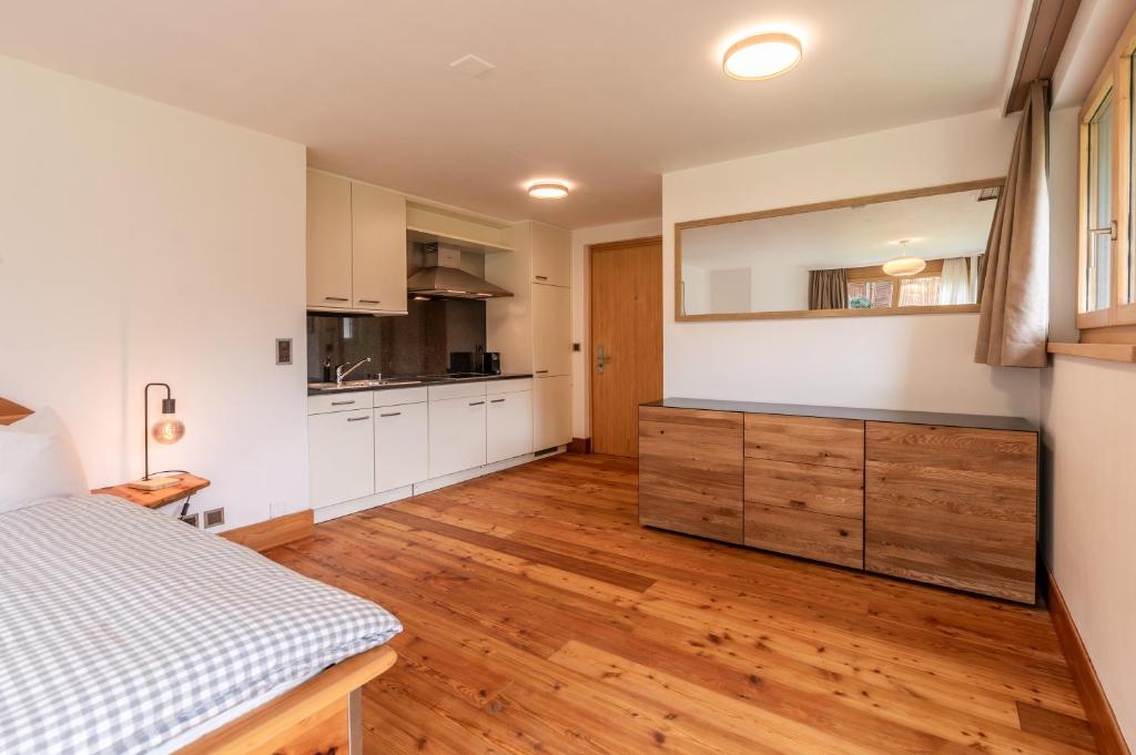 a kitchen with white cabinets and a wooden floor at Studio Haro in Zermatt