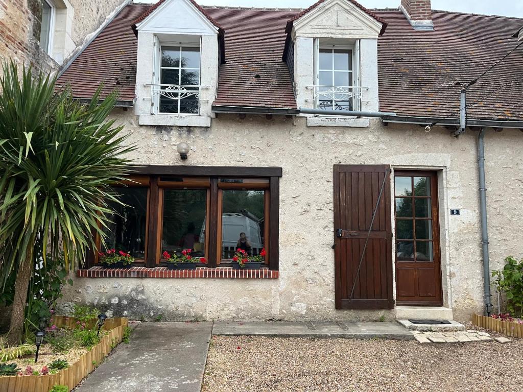 une maison avec une porte et des fleurs à une fenêtre dans l'établissement La maison du bourg, à Candé-sur-Beuvron