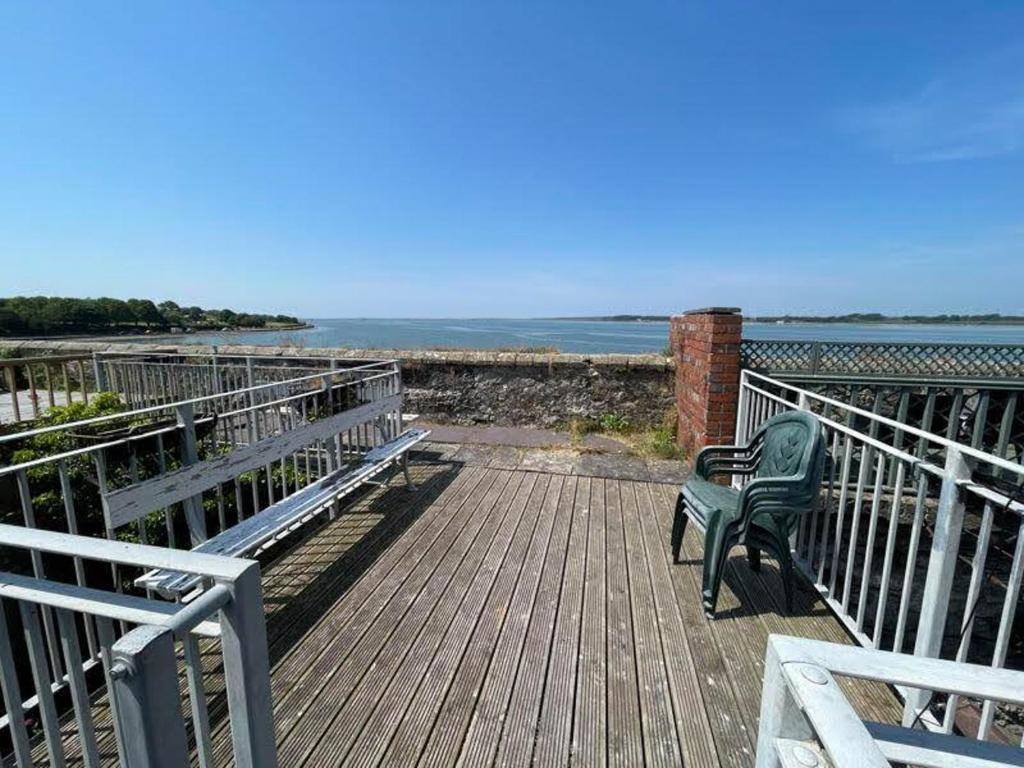 a bench sitting on a boardwalk near the ocean at Isfryn Holiday Let in Caernarfon