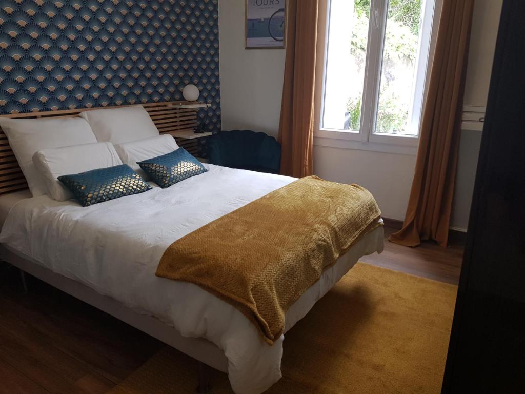 une chambre avec un lit avec des oreillers et une fenêtre dans l'établissement Maison cosy citadine, à Tours