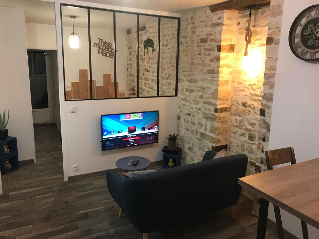 un salon avec un canapé et une télévision sur un mur dans l'établissement El Capullo - Appartement en Rdc avec cour en centre ville, à Châteauroux