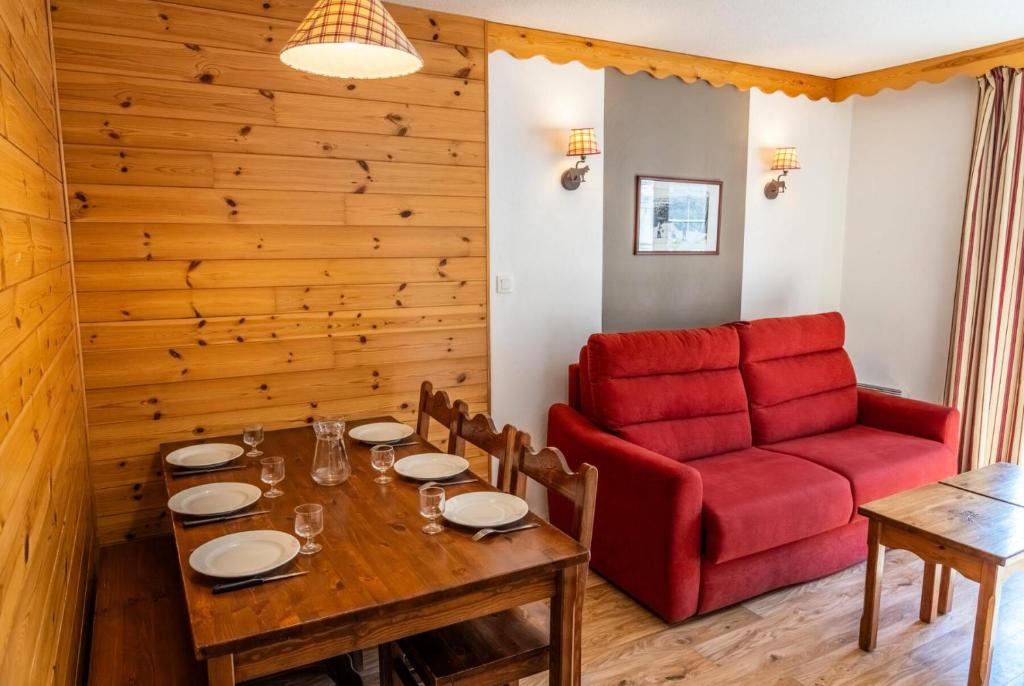 - une salle à manger avec une table et un canapé rouge dans l'établissement Résidence Les Hauts De Preclaux - Charmant appartement face aux pics des Orres MAE-3421, aux Orres