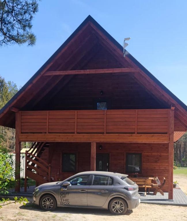 a car parked in front of a large wooden building at Domki letniskowe OSTROWITE in Ostrowite