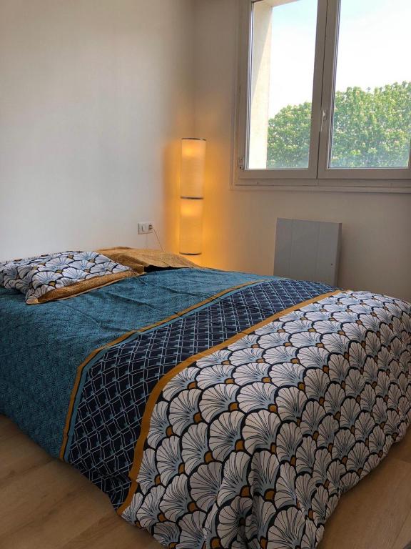 une chambre avec un lit avec une couette bleue et une fenêtre dans l'établissement Creteil new 1, à Créteil