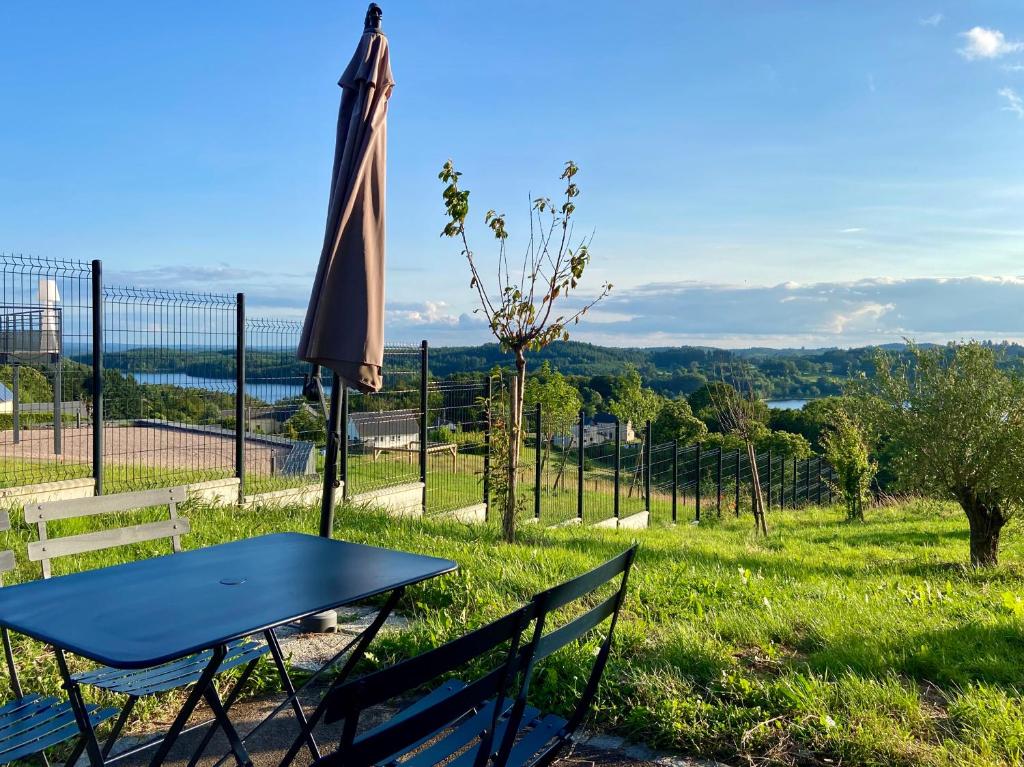 une table, des chaises et un parasol dans un champ dans l'établissement Appartement Belle-vue, à Liginiac