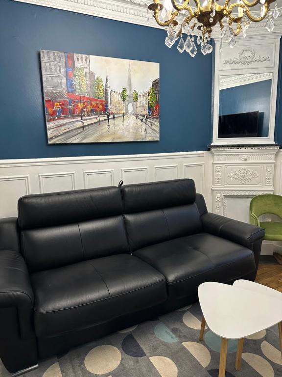 un salon avec un canapé noir et un tableau dans l'établissement Appartement calme près de La Villette, à Paris