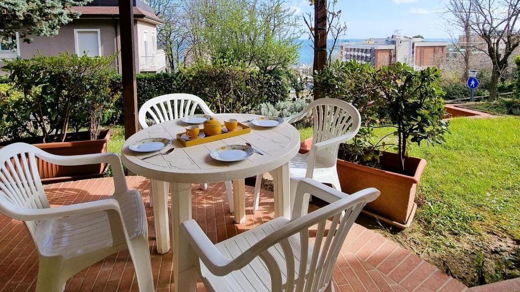 un tavolo bianco con sedie e frutta di Residence azzurro VISTA MARE-A a Gabicce Mare