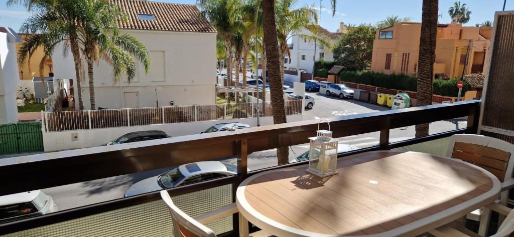 einen Holztisch auf einem Balkon mit Straßenblick in der Unterkunft Apartamento en complejo residencial con piscina in Puebla de Farnals