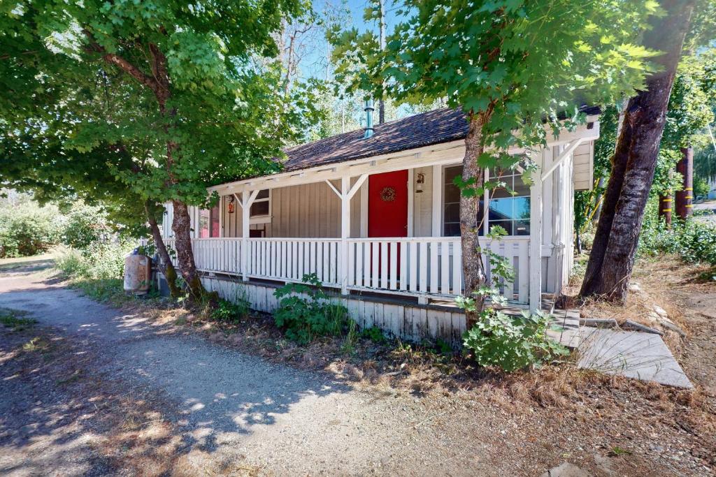 a white house with a red door and trees at Walk to Town! Dog-Friendly Quincy Getaway w/ Deck in Quincy