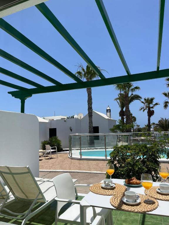 a patio with a table and chairs and a pool at Bungalow Retama in Tías
