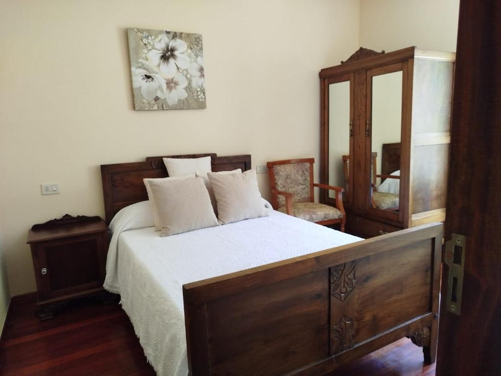 una camera da letto con letto con struttura in legno e specchio di Casa de Tanajildo a Lira
