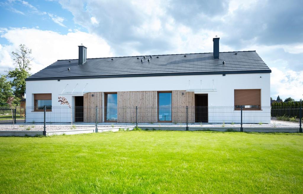 a large white building with a grass yard at Dom całoroczny w Sierakowie nr 2 in Sieraków