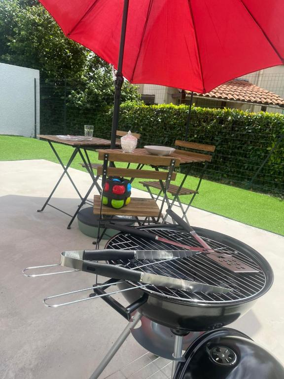 un gril avec un parapluie rouge dessus dans l'établissement La Vauréenne - Maison Chaleureuse avec parking, à Lavaur