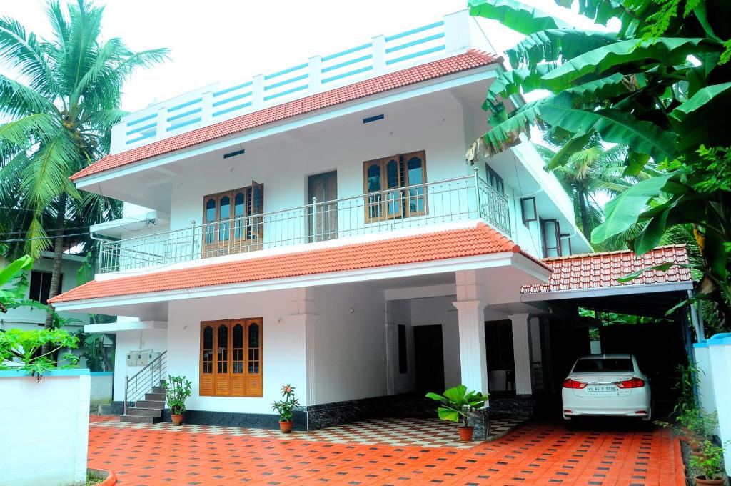 uma casa branca com um carro estacionado em frente dela em Grace Guest Home em Thrissur