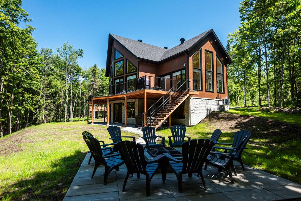 a house with a table and chairs in front of it at Lilia Chalet Urbain de Luxe près du Mont-Tremblant in Saint-Rémi-dʼAmherst