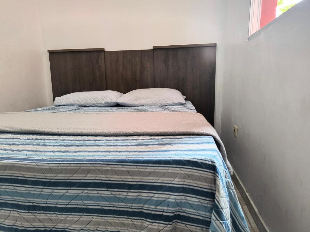 a bed with a wooden headboard in a bedroom at Apartamento aconchegante em Santana de Parnaíba SP in Santana de Parnaíba