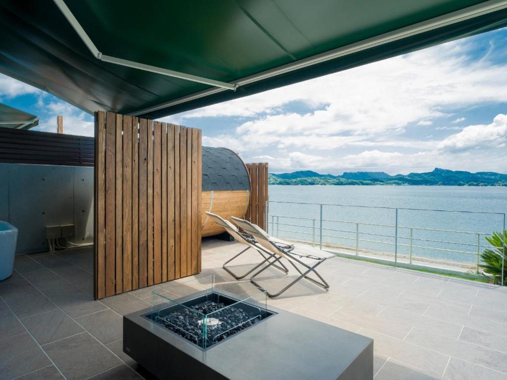 ein Balkon mit Tisch und Blick aufs Wasser in der Unterkunft Rakuten STAY HOUSE Amakusa 102 in Kami Amakusa