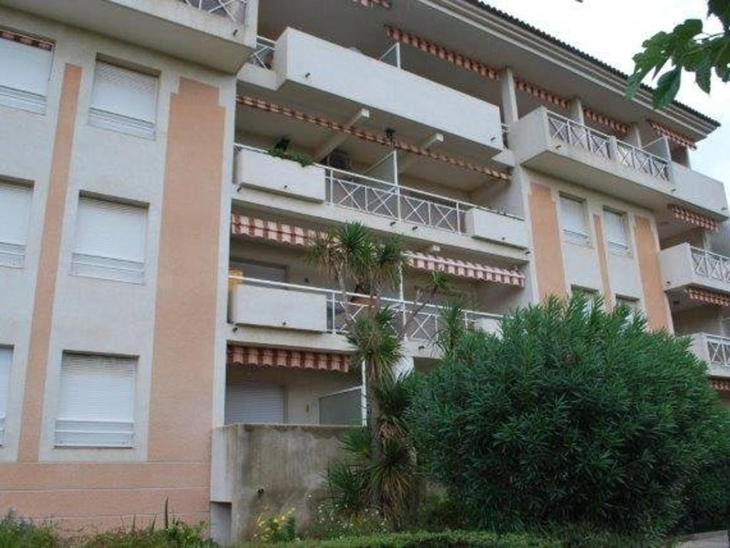 un immeuble avec des palmiers en face de celui-ci dans l'établissement Appartement 2 pièces confortable au Lavandou 34m² + terrasse, à 800m de la plage, 4 personnes. - FR-1-803-17, au Lavandou