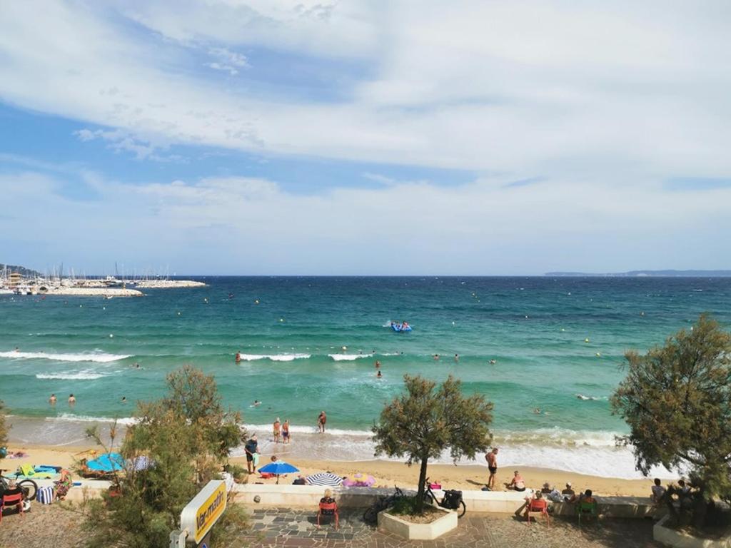 une plage avec un groupe de gens dans l'océan dans l'établissement T2 au Lavandou pour 4 avec parking, terrasse mer et accès plage - FR-1-803-23, au Lavandou