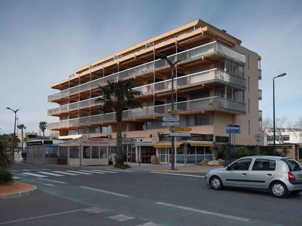 une voiture garée devant un grand bâtiment dans l'établissement Location T2 au Lavandou, terrasse, clim, parking, proche plage et centre, 4 couchages - FR-1-803-46, au Lavandou