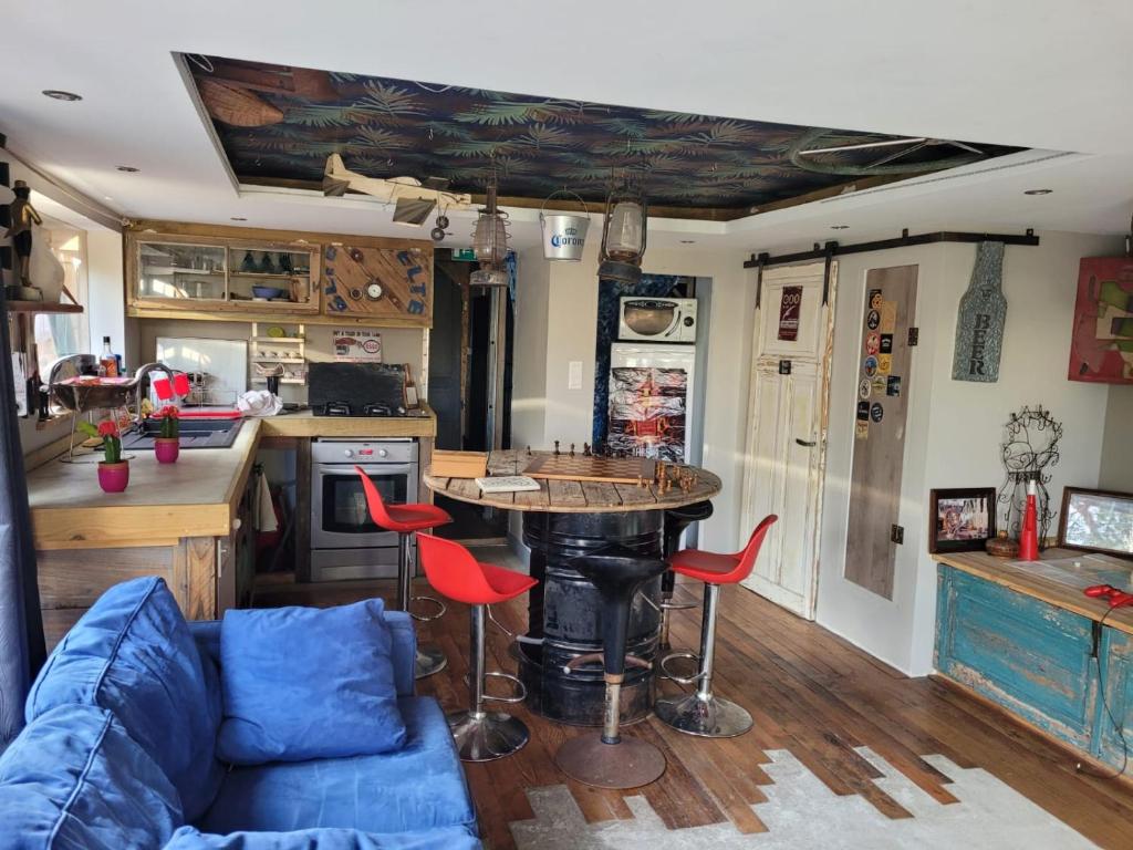 Il dispose d'une cuisine et d'un salon avec une table et des chaises rouges. dans l'établissement La cabane atypique, à Gujan-Mestras