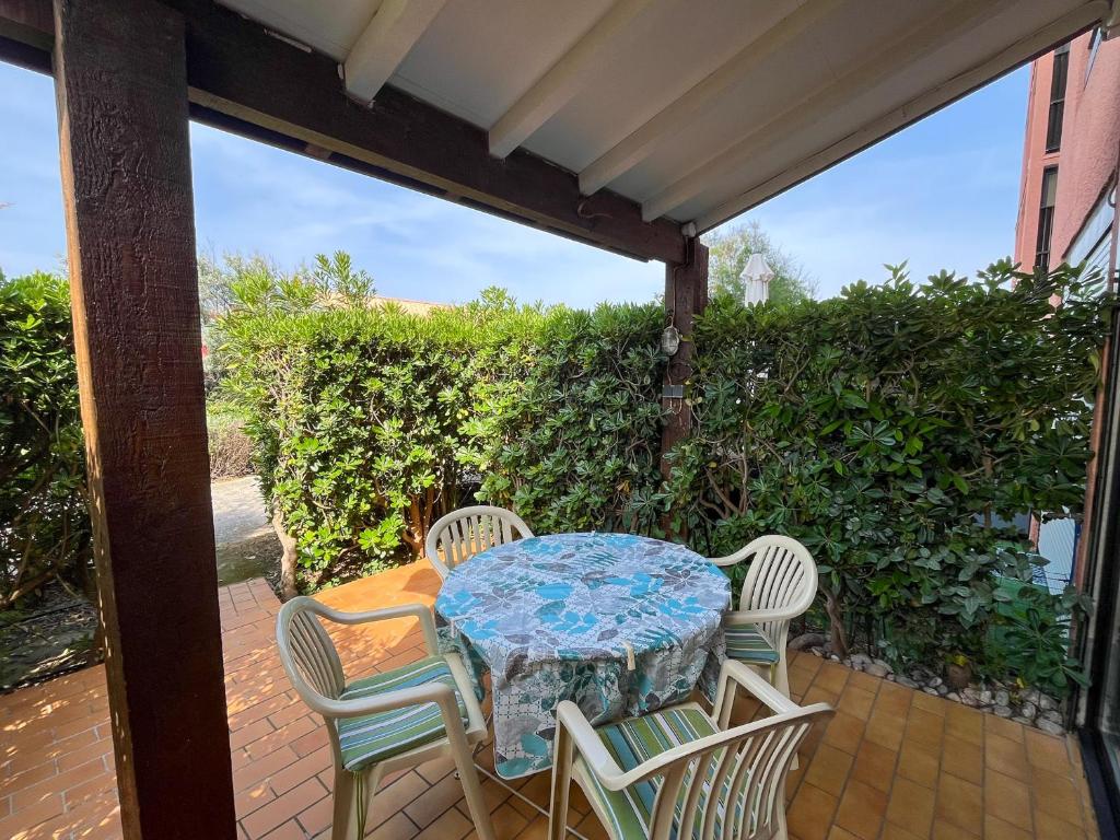 une table et quatre chaises sur la terrasse dans l'établissement Appartement T2 Rez-de-Jardin à Saint-Cyprien avec Accès Plage Direct et Piscine en Résidence - FR-1-753-22, à Saint-Cyprien