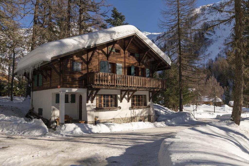 Chalet Ecureuil - Happy Rentals في شامونيه مون بلان: كابينة خشب عليها ثلج في الغابة