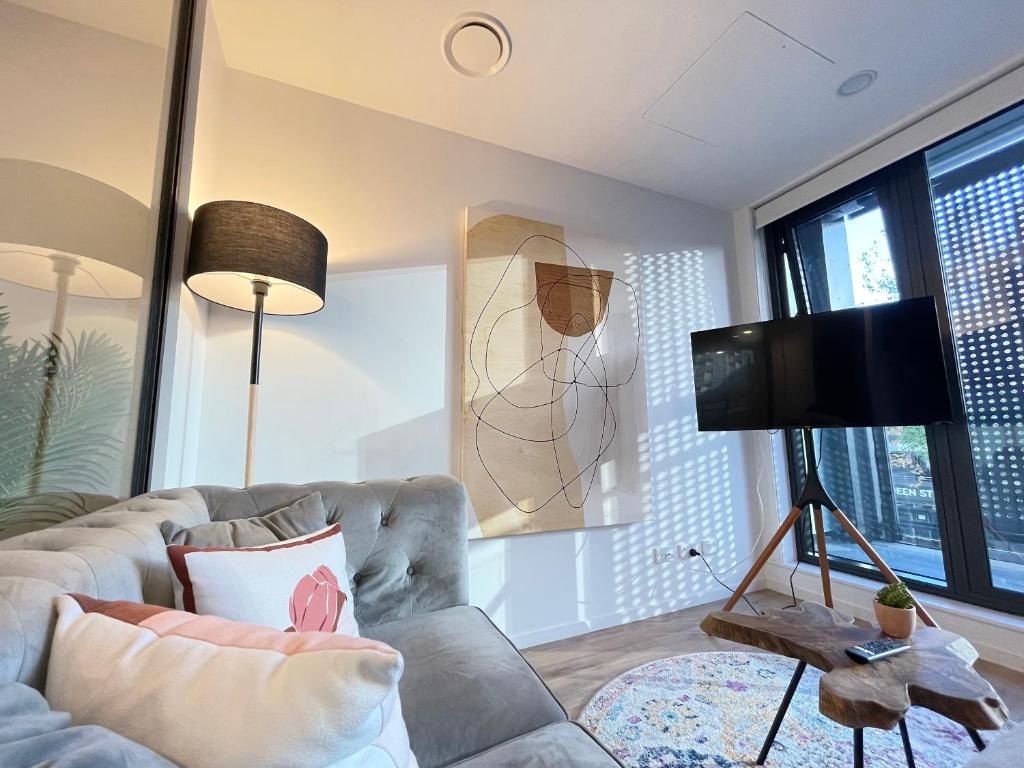 オークランドにあるBeautiful Stylish CBD apartmentのソファと薄型テレビのあるリビングルーム