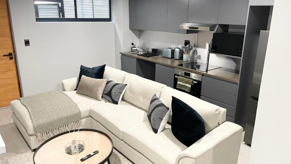 a living room with a white couch and a kitchen at The Onyx Umhlanga in Durban