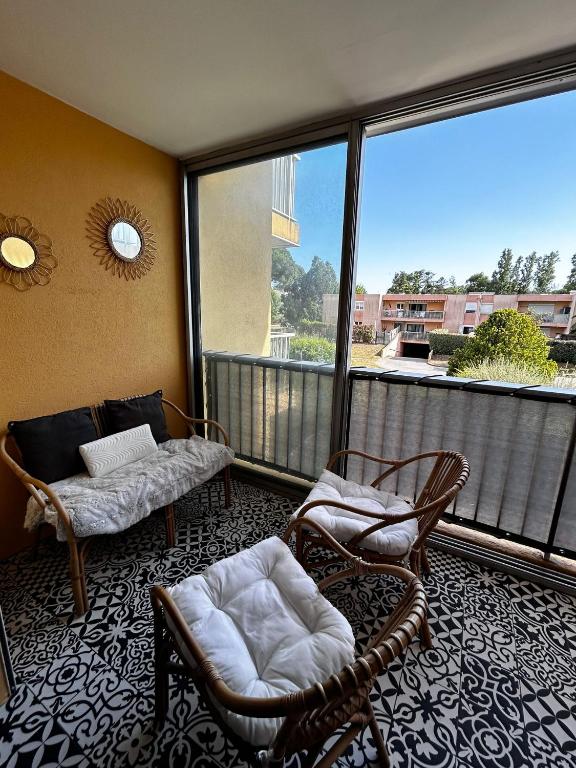 d'un balcon avec deux chaises, un canapé et une fenêtre. dans l'établissement Nid douillet à Frejus avec paking & loggia ensoleillée - Proche plages, à Fréjus