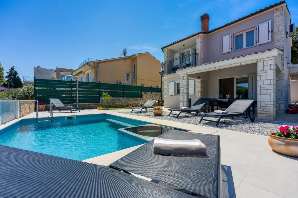 a backyard with a swimming pool and a house at Breeze Holiday Home - Sea View in Premantura