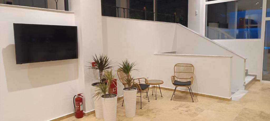 a living room with chairs and plants and a tv at Blue Bay Hotel in Iraklitsa