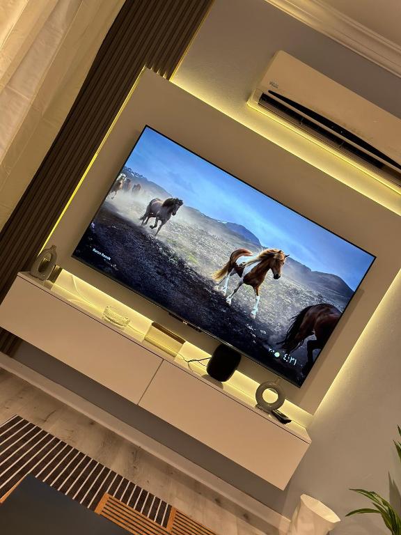 a flat screen tv with horses on it in a living room at شقة قباء r s 1 in Medina