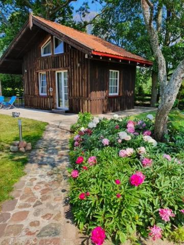 a small wooden cabin with flowers in front of it at Auci Guest house 2 in Liepāja