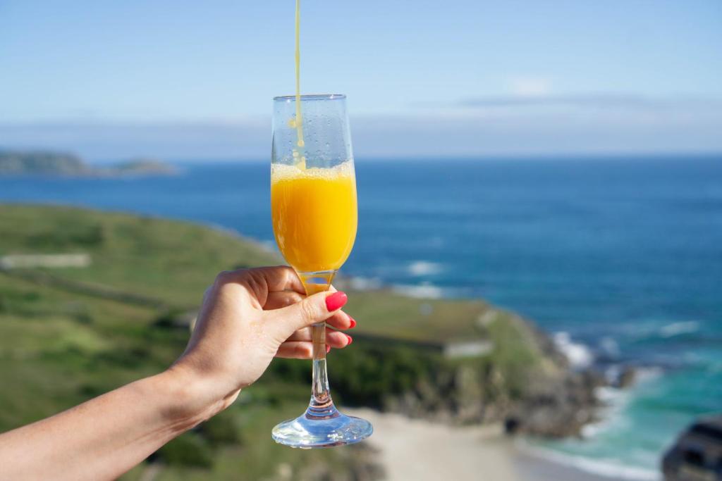 a hand holding a glass with an orange drink at GARA MALPICA, terraza al mar in Malpica