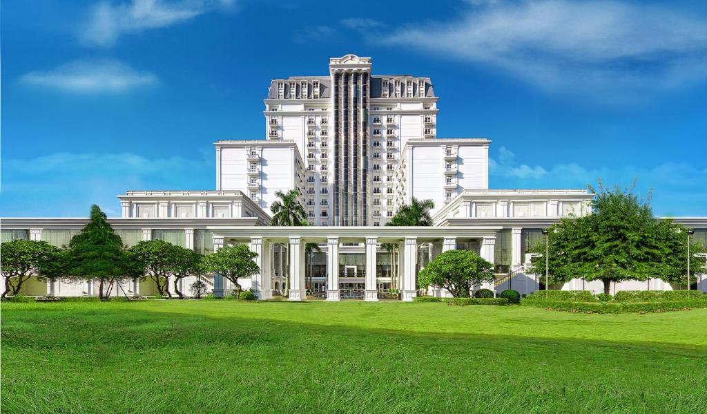 a large white building in front of a green field at Indochine Palace in Hue
