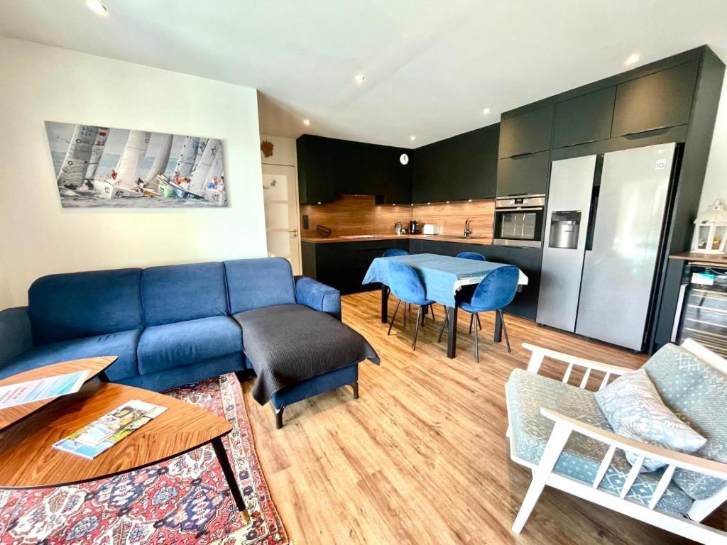 a living room with a blue couch and a kitchen at jolie résidence proche du centre ville à Roscoff in Roscoff