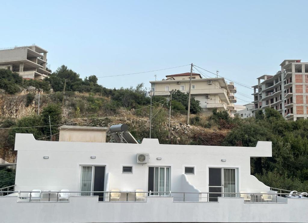 a white house on a ship with buildings in the background at Keivi Guesthouse in Sarandë