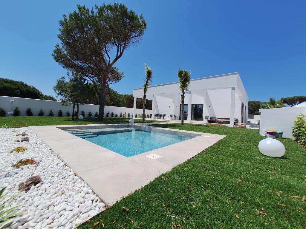 a house with a swimming pool in the yard at Poniente Beach House in Chiclana de la Frontera