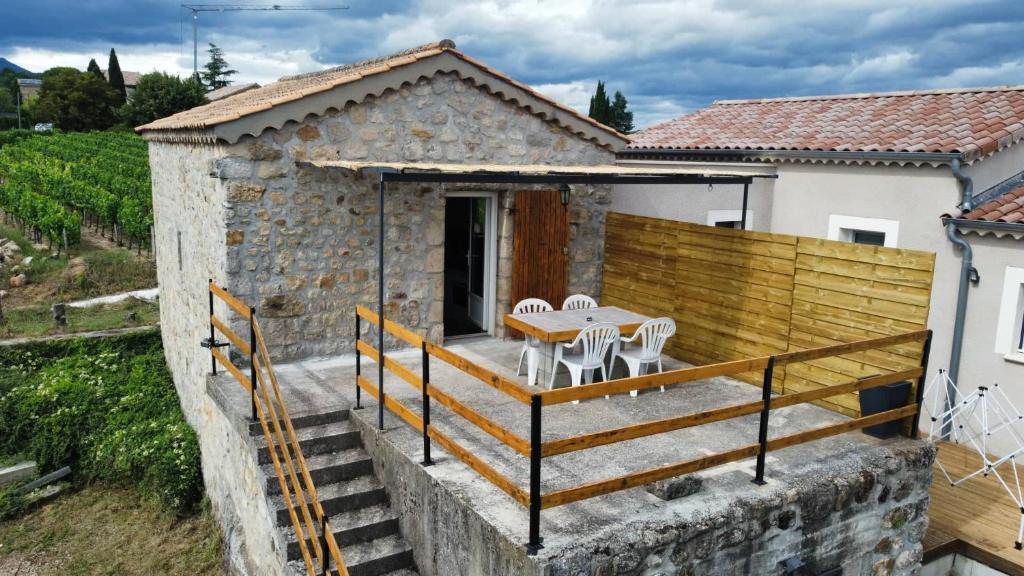 une maison avec une terrasse avec une table et des chaises dans l'établissement Studio maison en pierre avec terrasse, à Rosières